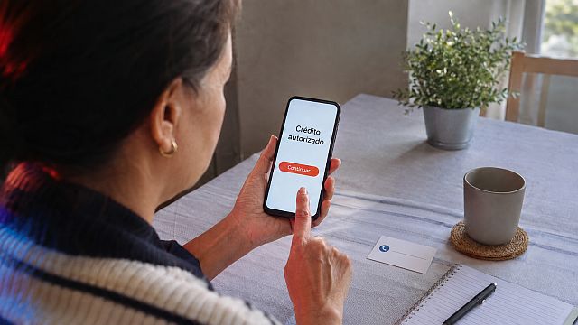 Persona verifica por otro canal un anuncio financiero sospechoso antes de compartir datos o realizar una transferencia.
