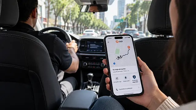 Pasajero consulta en su celular las funciones de seguridad de DiDi durante un viaje en automóvil